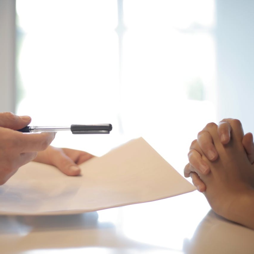 Person handing a document to another for signing
